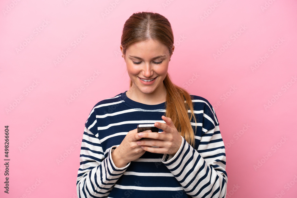 Young caucasian woman isolated on pink background sending a message with the mobile Young caucasian woman isolated on pink background sending a message with the mobile
