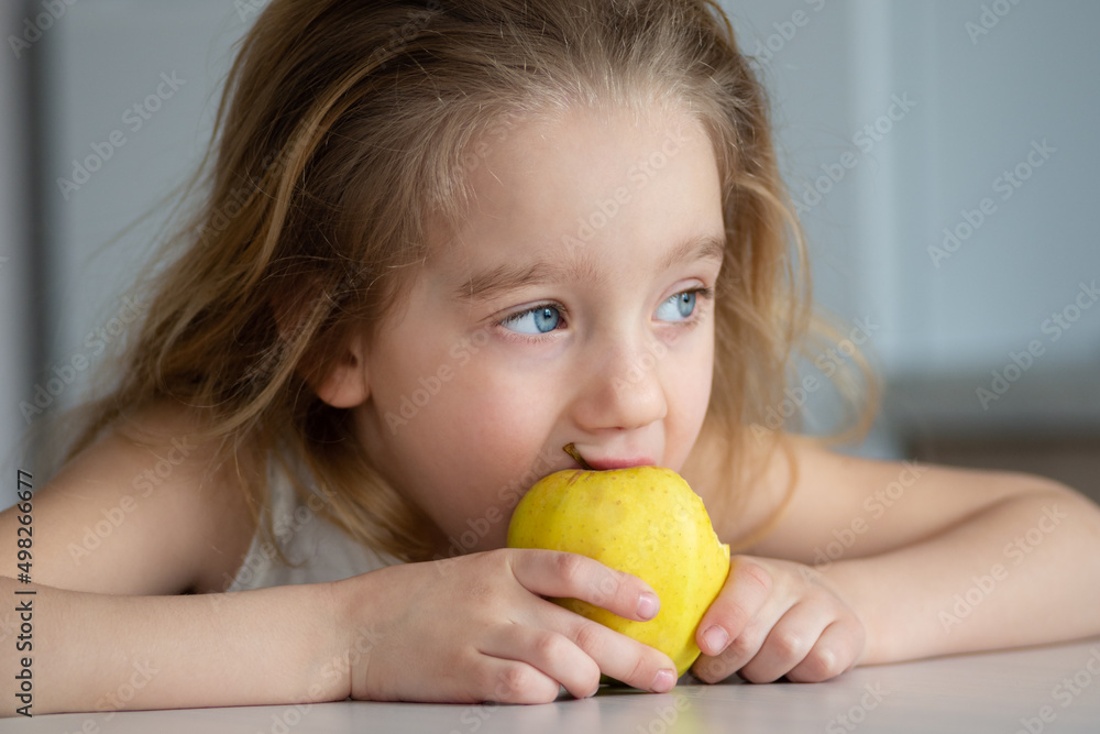 Portrait of a little blond girl smiling and eating an apple. The concept of healthy eating for children. Portrait of a little blond girl smiling and eating an apple. The concept of healthy eating for children.