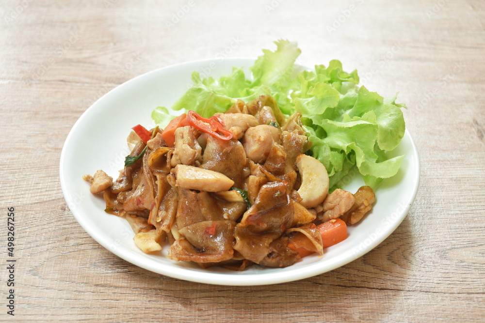 spicy fried large rice noodles with chicken and slice mushroom on plate spicy fried large rice noodles with chicken and slice mushroom on plate