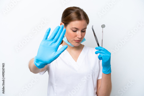 Dentist caucasian woman holding tools isolated on white background making stop gesture and disappointed