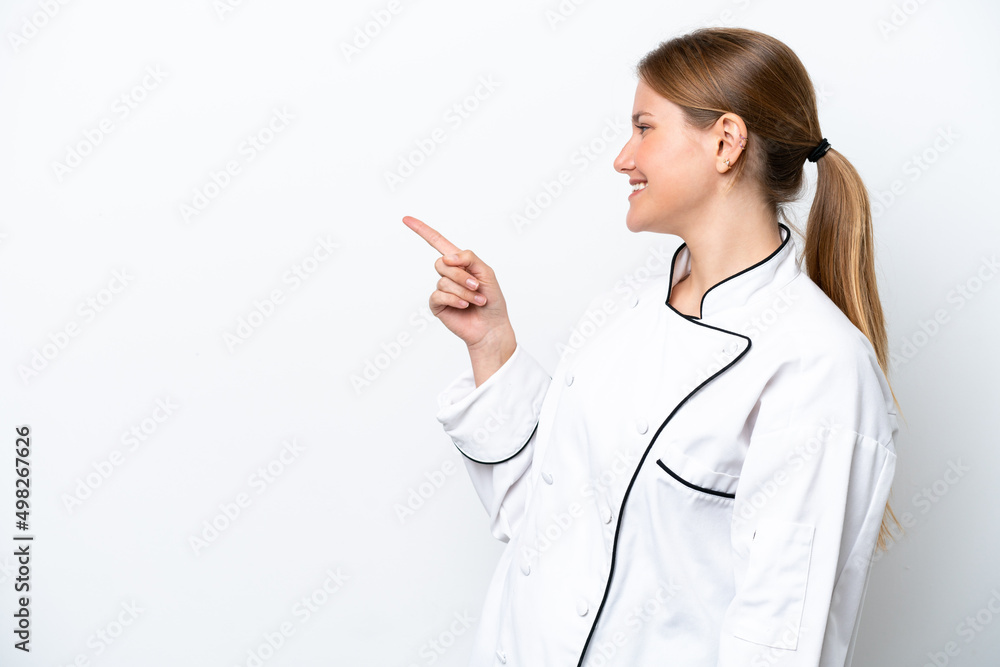 Young chef woman isolated on white background pointing finger to the side and presenting a product Young chef woman isolated on white background pointing finger to the side and presenting a product