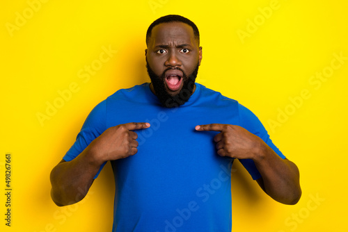 Portrait of attractive mad worried guy pointing at himself ask why me isolated over bright yellow color background
