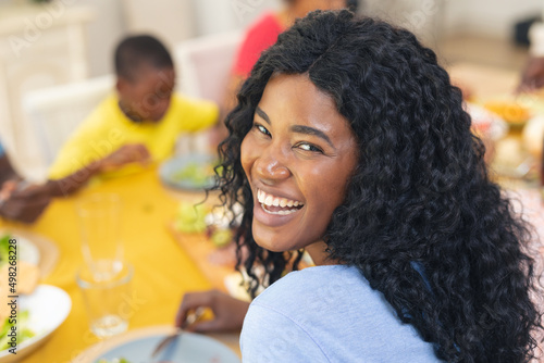 Portrait of happy african american mid adult woman having lunch with family on thanksgiving day