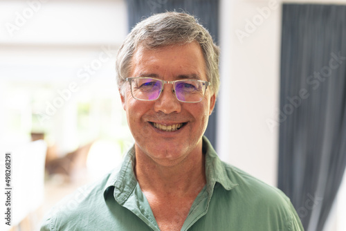 Portrait of smiling caucasian senior man in eyeglasses at home