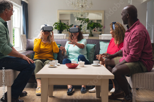 Multiracial senior woman and men with friends using vr headsets at home