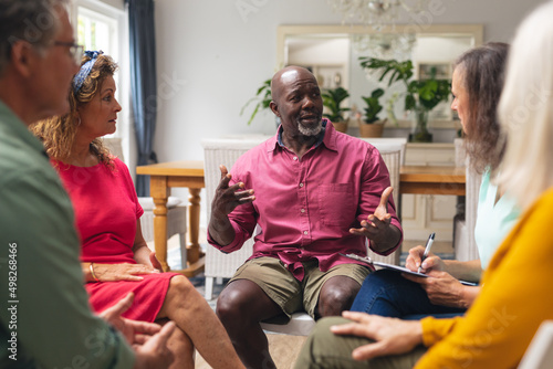 Midsection of multiracial senior males and females discussing during group therapy session