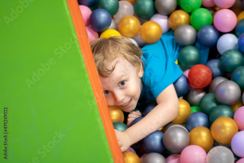 Cute four year old blond child playing colorful balls, top view.