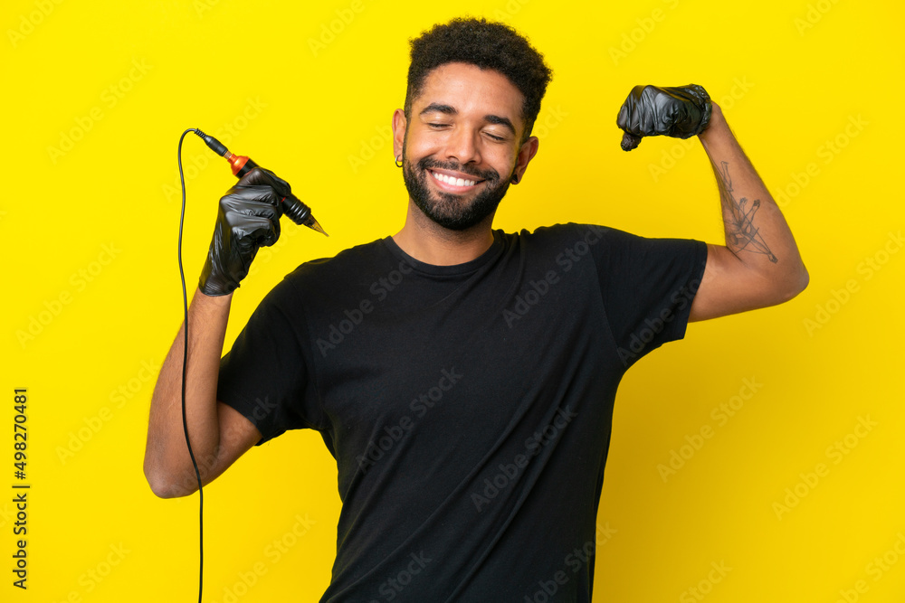 Tattoo artist man Brazilian man isolated on yellow background doing strong gesture Tattoo artist man Brazilian man isolated on yellow background doing strong gesture