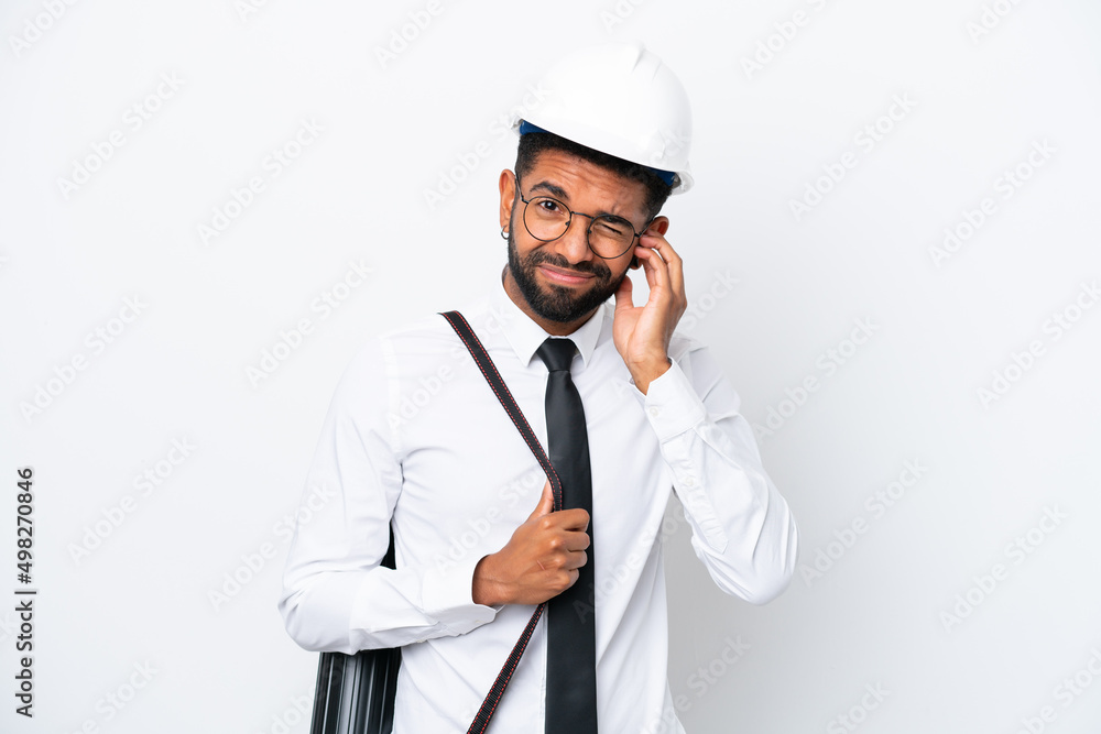 Young architect Brazilian man with helmet and holding blueprints isolated on white background frustrated and covering ears