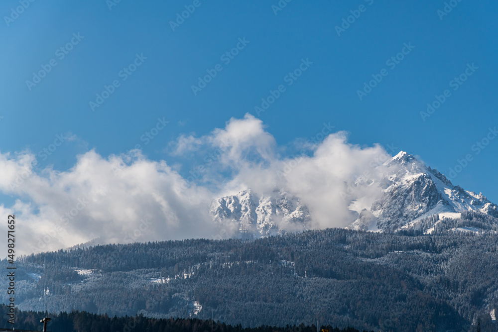 Blauer Himmel und schneebedeckter Berg in Wolken gehüllt