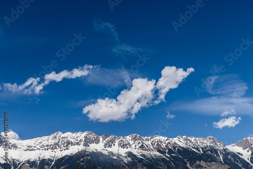 Schneebedeckte Nordkette bei Innsbruck mit blauem Himmel und Föhnwolken photo