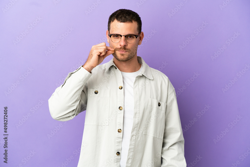 Brazilian man over isolated purple background showing a sign of silence gesture Brazilian man over isolated purple background showing a sign of silence gesture