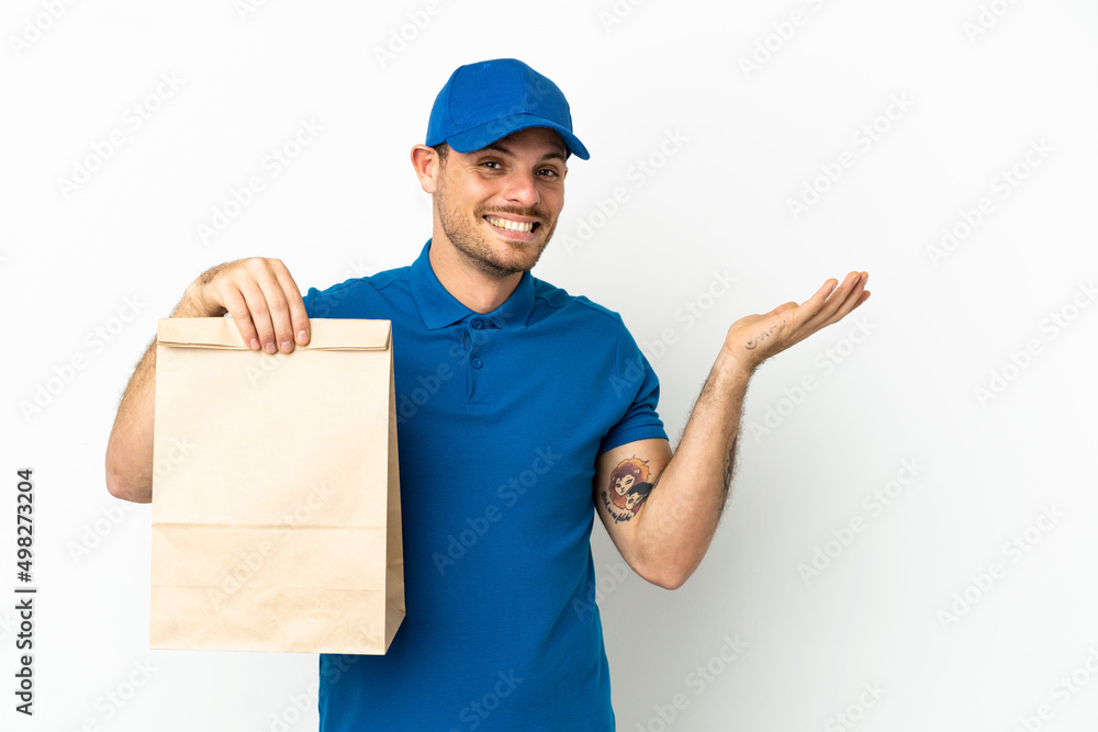 Brazilian taking a bag of takeaway food isolated on white background extending hands to the side for inviting to come Brazilian taking a bag of takeaway food isolated on white background extending hands to the side for inviting to come