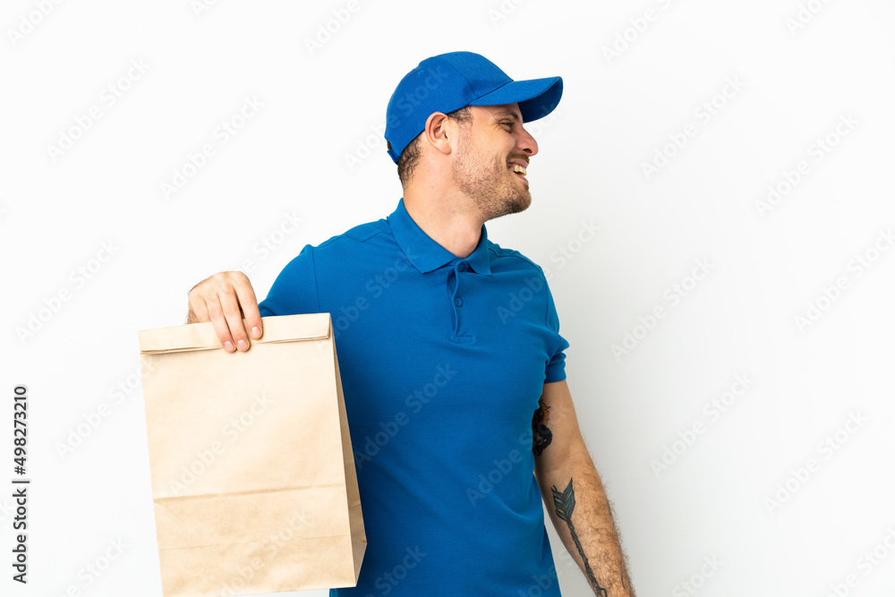 Brazilian taking a bag of takeaway food isolated on white background laughing in lateral position Brazilian taking a bag of takeaway food isolated on white background laughing in lateral position