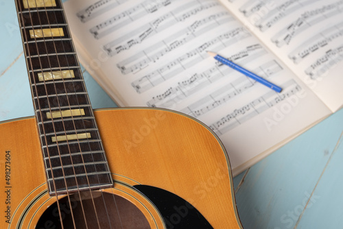 Music recording scene with guitar, music sheets and pencil on wooden table, closeup