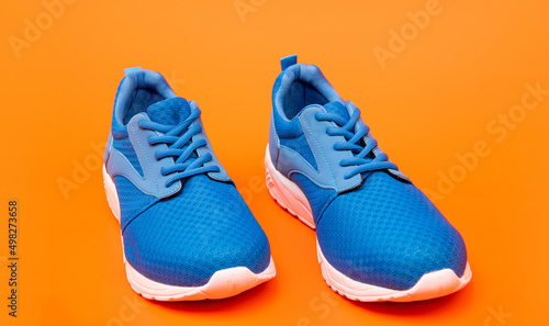 pair of footwear for training on orange background, jogging shoes