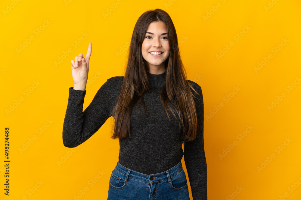 Teenager Brazilian girl isolated on yellow background pointing up a great idea Teenager Brazilian girl isolated on yellow background pointing up a great idea