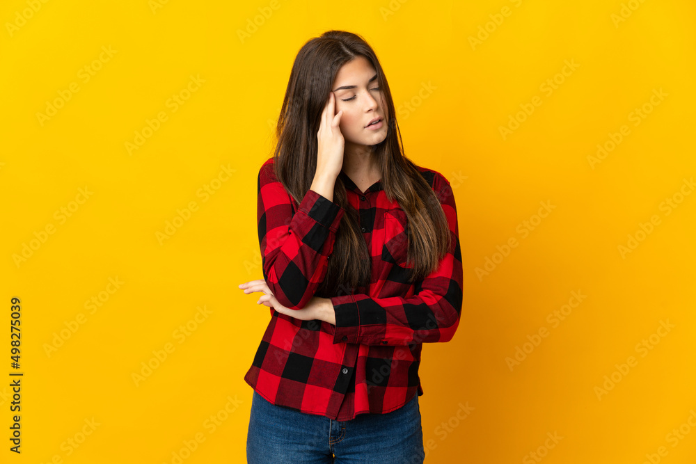 Teenager Brazilian girl isolated on yellow background with headache Teenager Brazilian girl isolated on yellow background with headache
