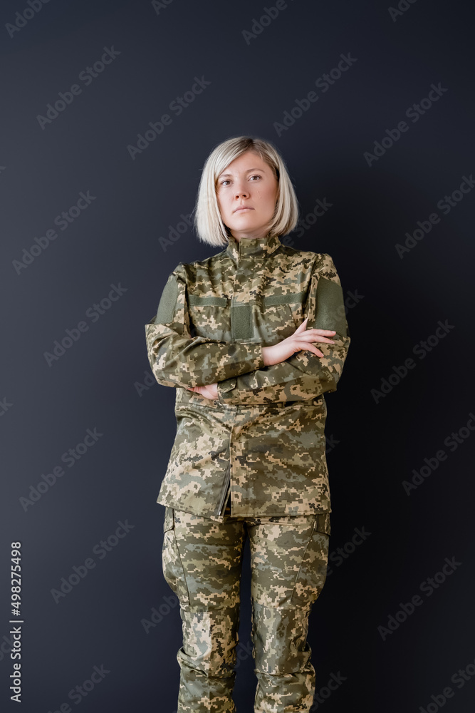 serious woman in camouflage standing with crossed arms isolated on black. serious woman in camouflage standing with crossed arms isolated on black.