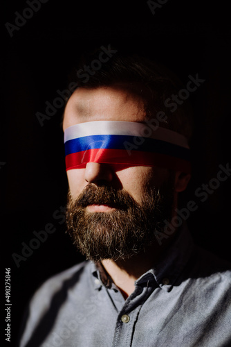 Man with Russian flag blindfold on black background, Russian propaganda closed people's eyes concept.
