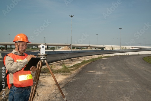 Engineer or surveyor working with theodolite  equipment at road construction site.