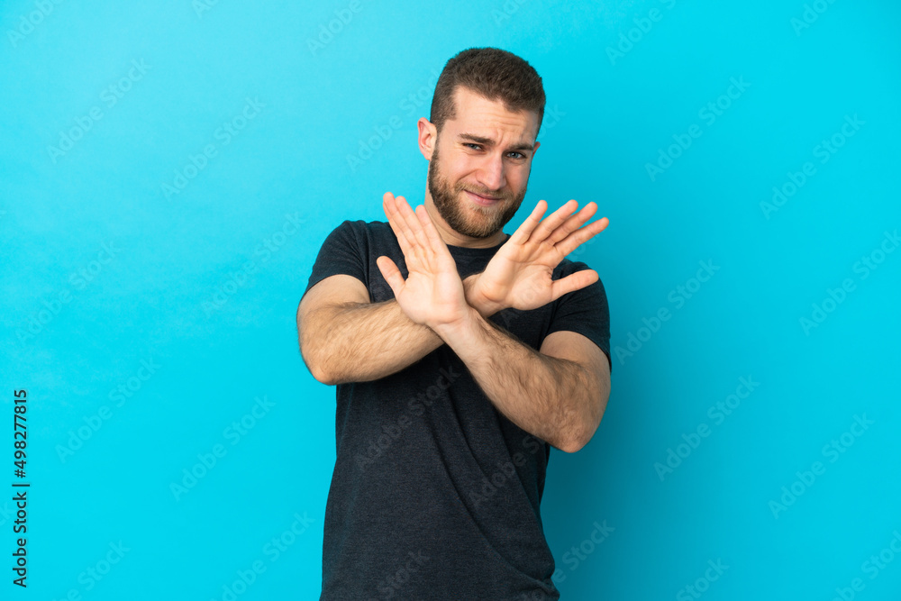 Naklejka premium Young handsome caucasian man isolated on blue background nervous stretching hands to the front