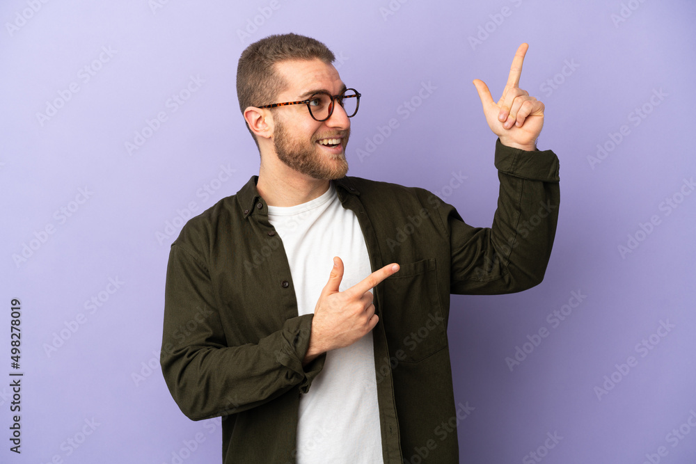 Young handsome caucasian man isolated on purple background pointing with the index finger a great idea Young handsome caucasian man isolated on purple background pointing with the index finger a great idea