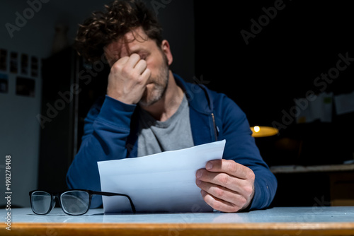 Ein Mann mit Sorgen hat einen unangenehmen Brief in der Hand, eine unbezahlbare Mahnung oder Kündigung.