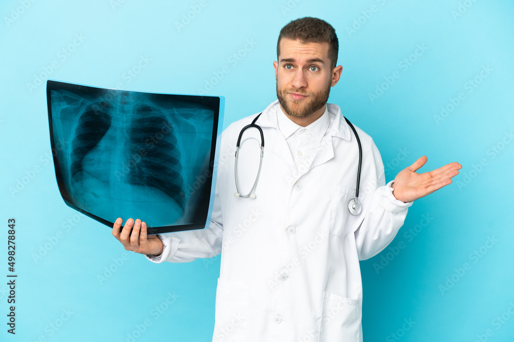 Professional traumatologist isolated on blue background having doubts while raising hands Professional traumatologist isolated on blue background having doubts while raising hands