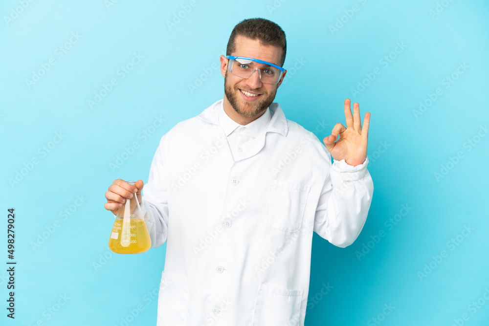 Young caucasian scientific man isolated on blue background showing ok sign with fingers