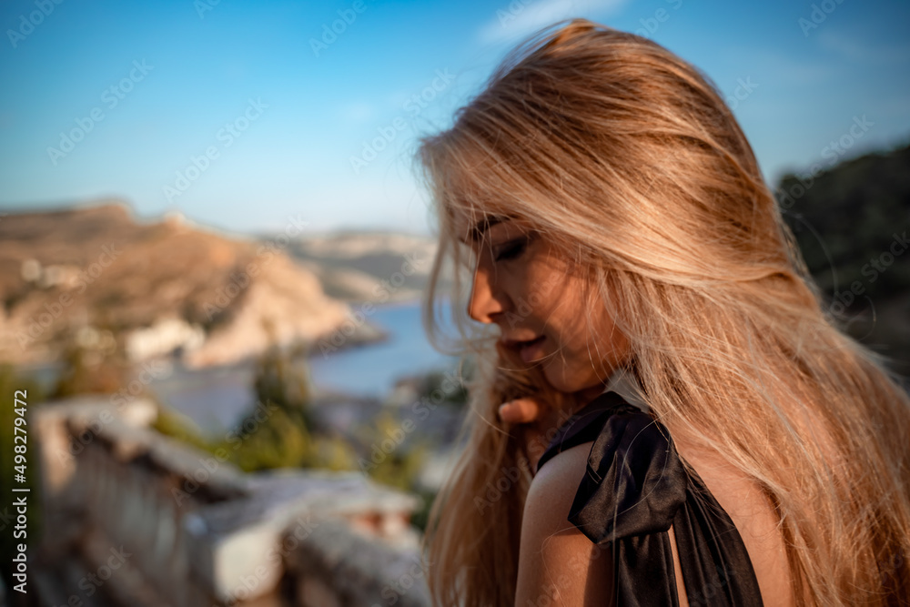 Blonde long hair, nature summer happy adult girl with long blond hair developing in the wind in nature. Dressed in a black top, white skirt. Blonde long hair, nature summer happy adult girl with long blond hair developing in the wind in nature. Dressed in a black top, white skirt.