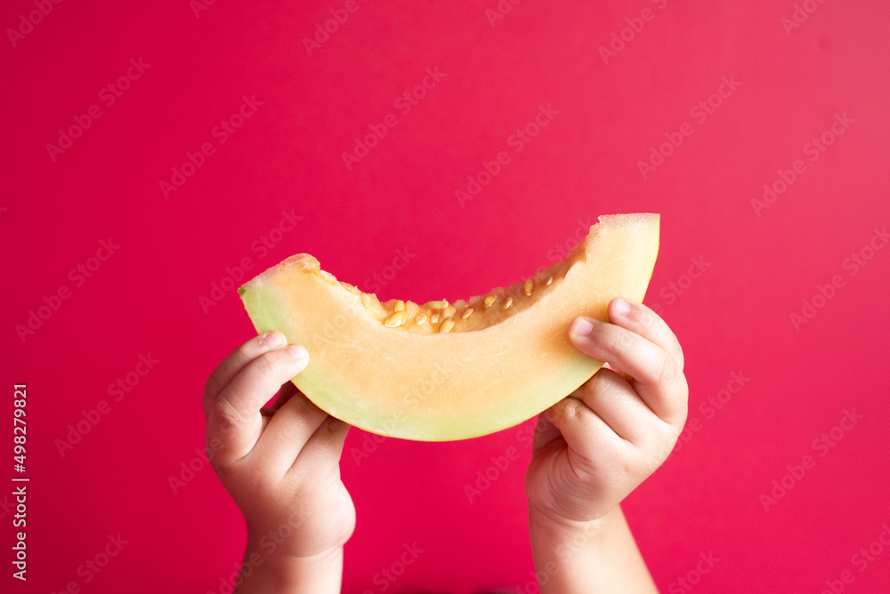 Ταπετσαρία Little child hand holding a honeydew melon or rockmelon against pink background