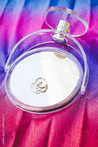 Two silver weading rings over a mirror against a rainbow background photo