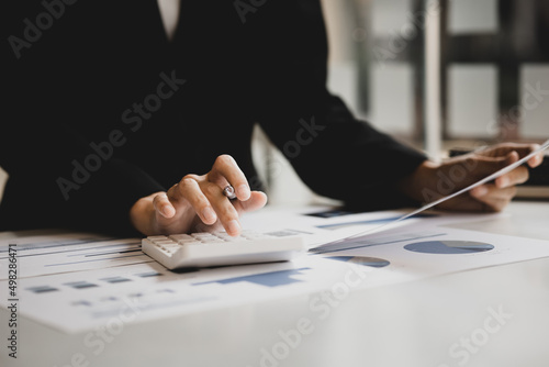 Business woman using a calculator to calculate numbers on a company's financial documents, he is analyzing historical financial data to plan how to grow the company. Financial concept.