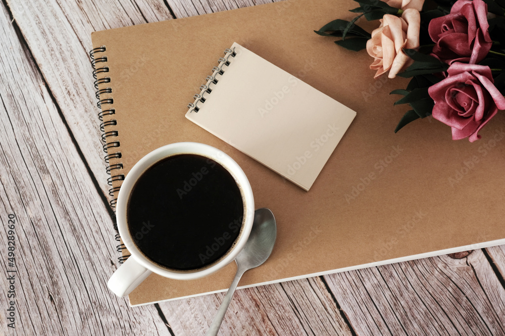 black coffee with notebook and rose on wooden table