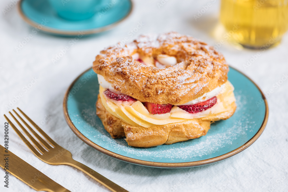 Traditional French Dessert called Paris Brest on a light grey background with powder sugar and strawberries Traditional French Dessert called Paris Brest on a light grey background with powder sugar and strawberries