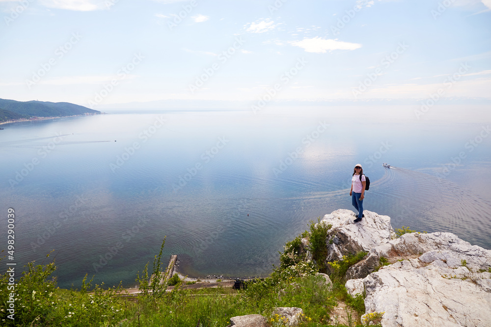 Obraz premium A woman is traveling on Lake Baikal. Beautiful view from the cliff at the port of Baikal on a summer day. 