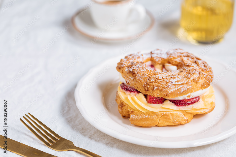 Traditional French Dessert called Paris Brest on a light grey background with powder sugar and strawberries Traditional French Dessert called Paris Brest on a light grey background with powder sugar and strawberries