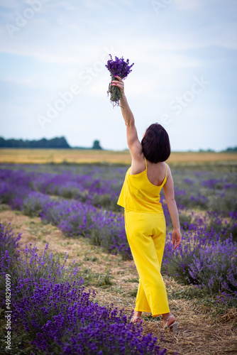 Fototapeta Naklejka Na Ścianę i Meble -  Ukrainian girl in a yellow suit picked up a bouquet of lavender on the field. Purple is a very beautiful color. Selective focus