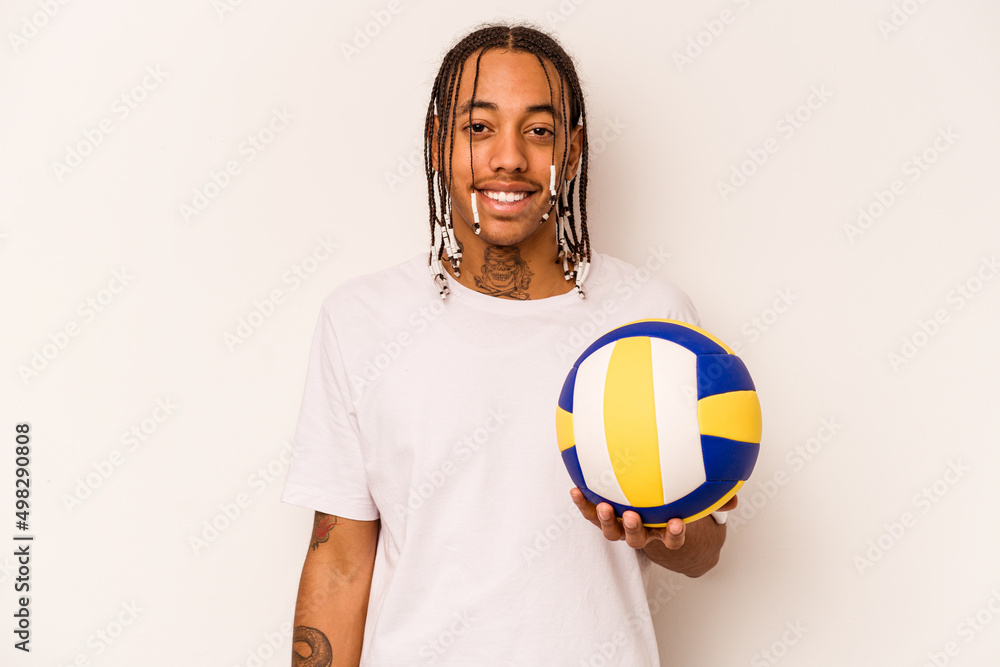 Young African American man playing volleyball isolated on white background laughing and having fun.