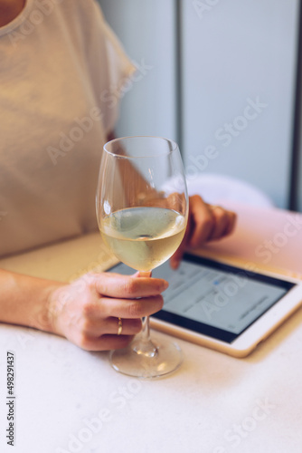 Young woman drinks wine while scrolling on tablet