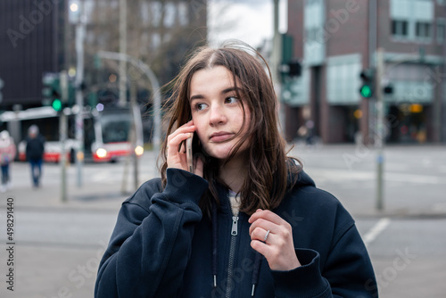 A young woman talking on the phone in the city on the street.