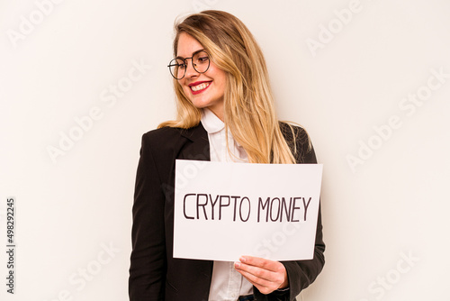 Young business caucasian woman holding a crypto money placard isolated on white background looks aside smiling, cheerful and pleasant.