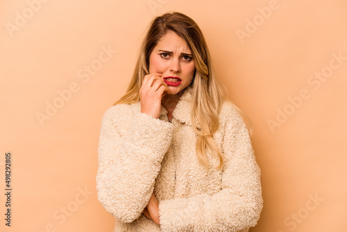 Young caucasian woman isolated on beige background biting fingernails, nervous and very anxious. © Asier