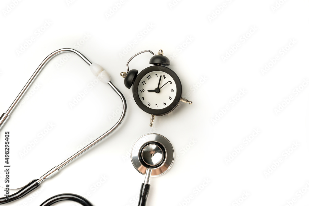 Stethoscope and alarm clock isolated on white background closeup. The concept of the need for timely medical diagnosis. Stethoscope and alarm clock isolated on white background closeup. The concept of the need for timely medical diagnosis.