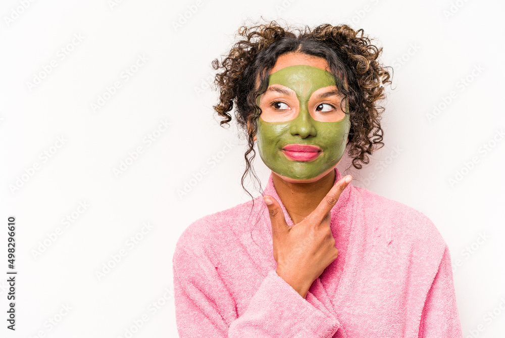 Young hispanic woman wearing a facial mask isolated on white background looking sideways with doubtful and skeptical expression. Young hispanic woman wearing a facial mask isolated on white background looking sideways with doubtful and skeptical expression.