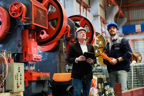 lathe and stamping metal machine. Caucasian business man and Factory engineer in hard hat helmet talking and discussion at Heavy Industry Manufacturing Factory.