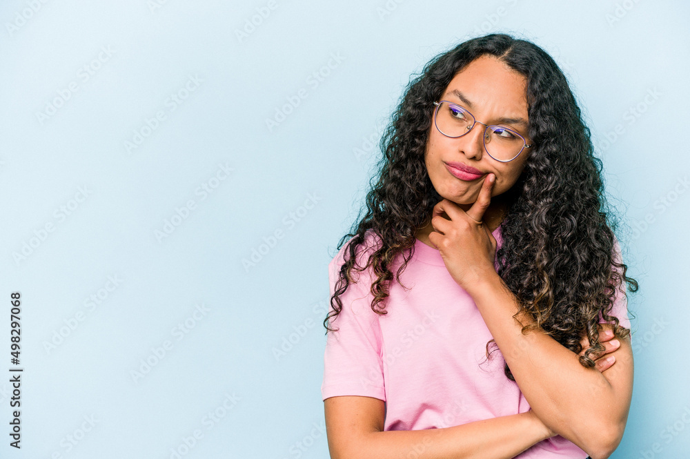 Young hispanic woman isolated on blue background looking sideways with doubtful and skeptical expression. Young hispanic woman isolated on blue background looking sideways with doubtful and skeptical expression.