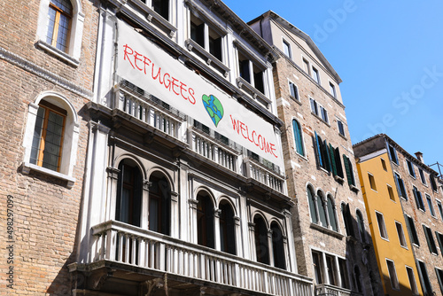 Banner with phrase WELCOME REFUGEES on building outdoors