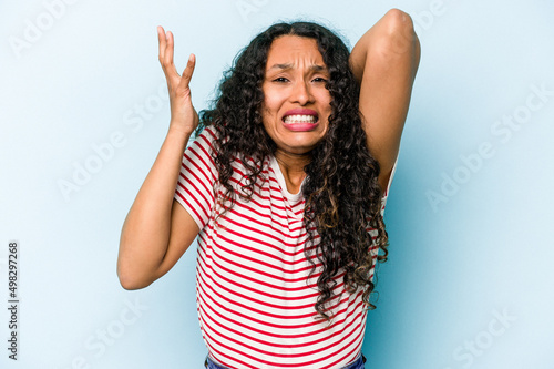 Young hispanic woman isolated on blue background screaming with rage.